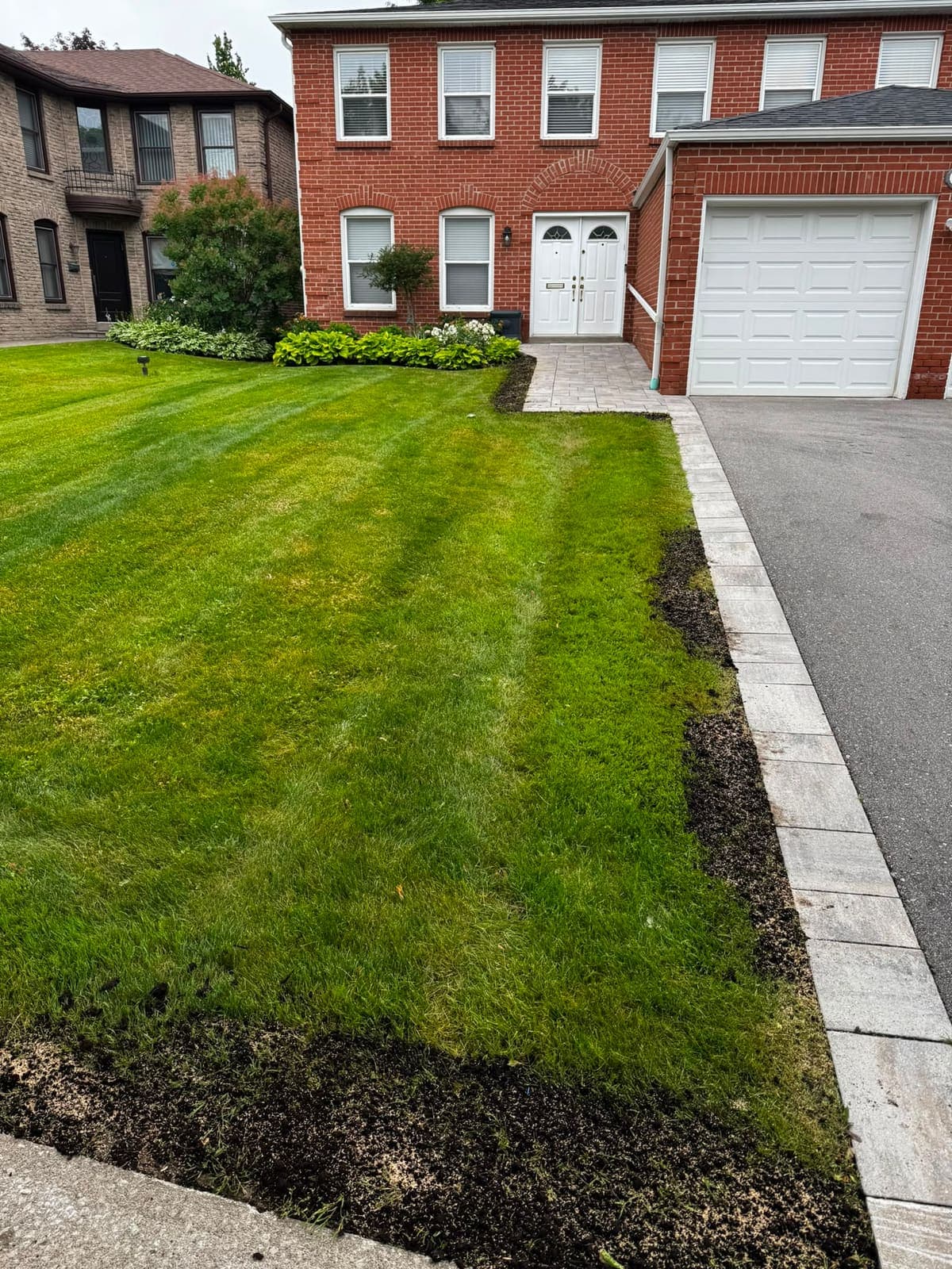 Red-brick home with a paver walkway and soldier-course driveway border
